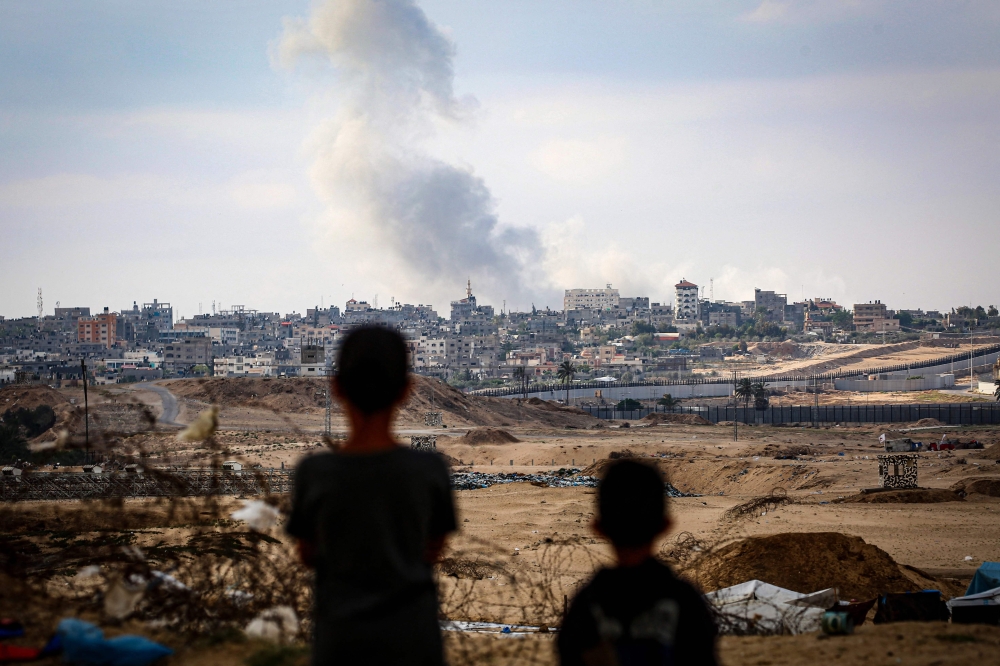 Boys watch smoke billowing during Israeli strikes east of Rafah in the southern Gaza Strip on May 13, 2024, amid the ongoing conflict between Israel and the Palestinian militant group Hamas. — AFP pic