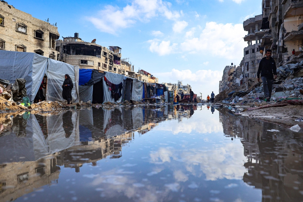 Displaced Palestinians walk around a puddle in front of destroyed buildings and tents in Khan Yunis in the southern Gaza Strip on May 16, 2024, amid the ongoing conflict between Israel and the militant group Hamas. — AFP pic