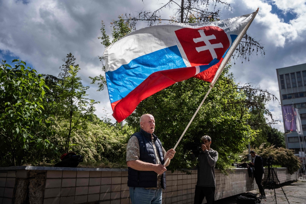 Picture taken on May 16, 2024 shows a man named Vladimir Petko holding a Slovakia flag, who came to pray in front of the hospital in Banska Bystrica, Slovakia where Slovak Prime Minister Robert Fico is being treated after he was shot 