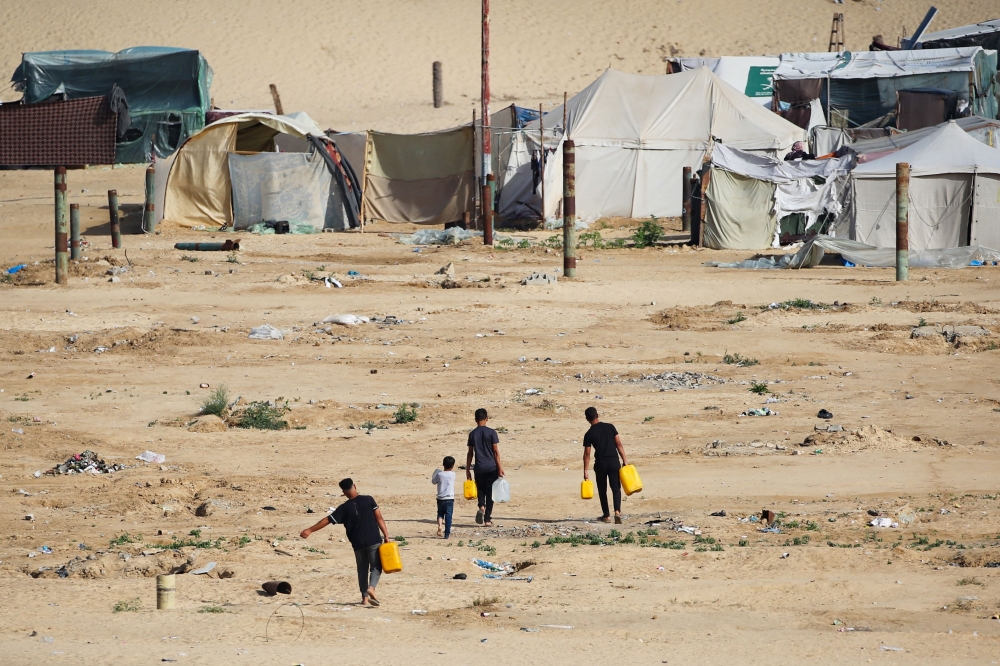 Displaced Palestinians carry water cans back to their tents at a temporary camp in Rafah on May 17, 2024, amid the ongoing conflict between Israel and Hamas. — AFP pic