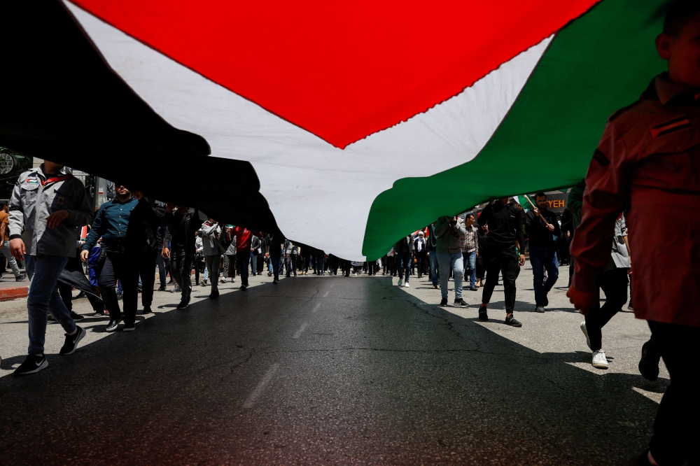 Palestinians hold a Palestinian flag as they take part in a protest to mark the 76th anniversary of the Nakba, the 