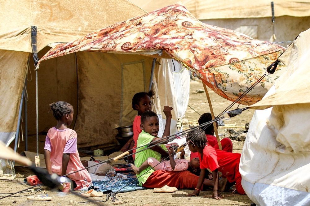 File photo of children siting in the shade of a sheet outside a tent at a camp for people displaced by conflict in Sudan’s eastern Gedaref province on May 15, 2024. — AFP pic