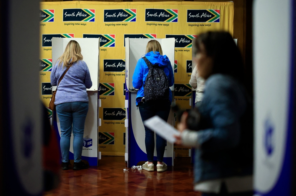 People mark their ballot papers as they vote in the South African general election, at the South African High Commission in central London on May 18, 2024. — AFP pic