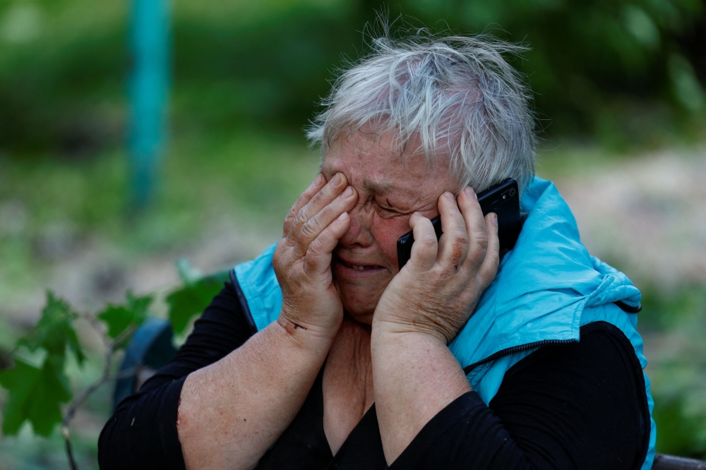 A woman reacts as she speaks via a phone about a death of her relative at a resort area, amid Russia's attack on Ukraine, in Kharkiv, Ukraine May 19, 2024. — Reuters pic