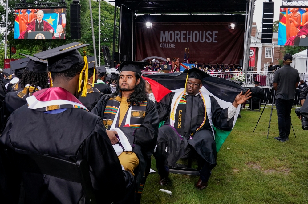 A Morehouse College graduate with his back turned, holds a Palestinian flag while US President Joe Biden speaks during a commencement ceremony. — Reuters pic