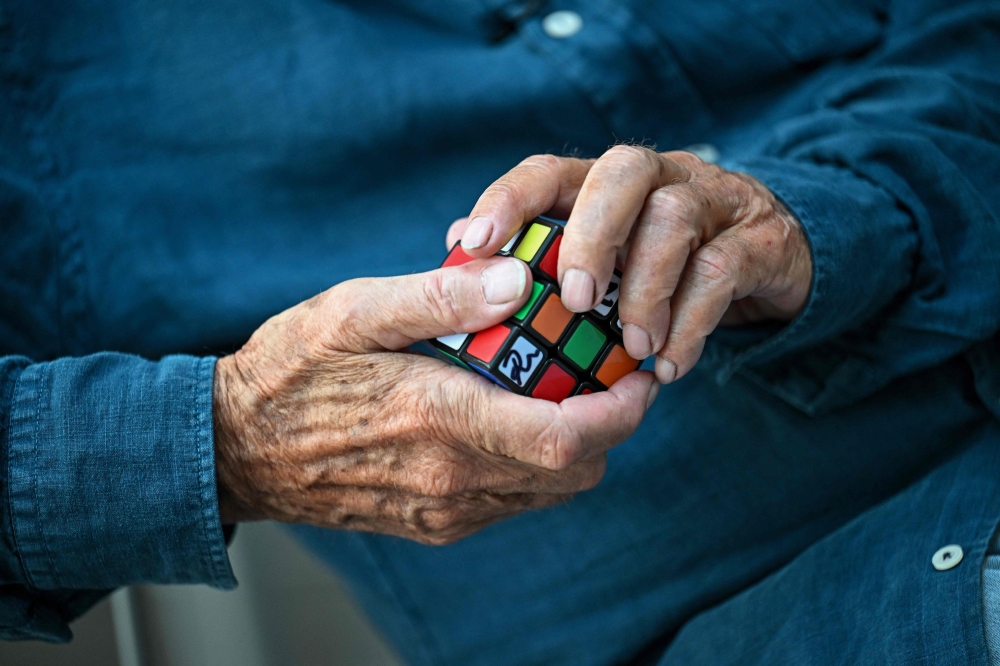 Hungarian inventor Erno Rubik holds a Rubik's Cube 3D puzzle in his hands during an interview with AFP. — AFP pic