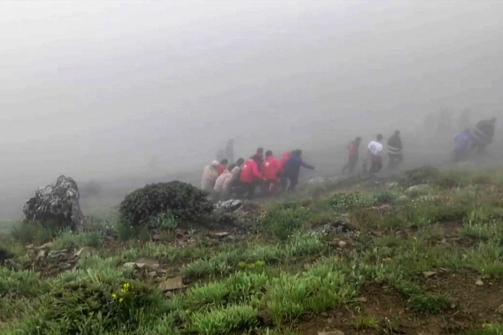 This grab taken from handout video footage released by the Iranian Red Cescent on May 20, 2024 shows rescuers recovering bodies at the site of President Ebrahim Raisi’s helicopter crash in a fog-shrouded mountainous area of northwest Iran. — AFP pic/Iranian Red Crescent