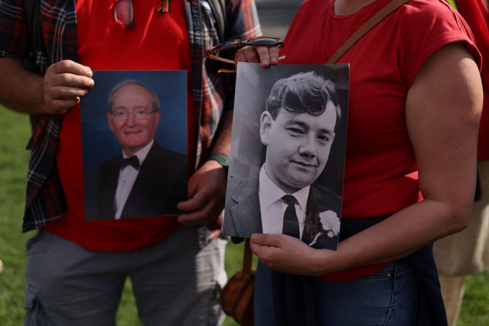 A woman holds a picture of her father, Tony Owen, and a man holds a picture of her step-father, Anthony Higgs, both victims of the contaminated blood scandal, as people gather for a vigil to remember those that lost their lives, ahead of the release of the final report of the Infected Blood Inquiry, in London, Britain, May 19, 2024. — Reuters pic
