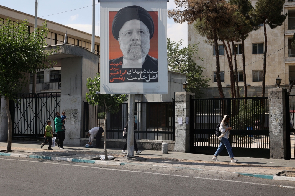 People walk near a banner with a picture of the late Iran's President Ebrahim Raisi on a street in Tehran, Iran May 20, 2024. — Wana pic via Reuters
