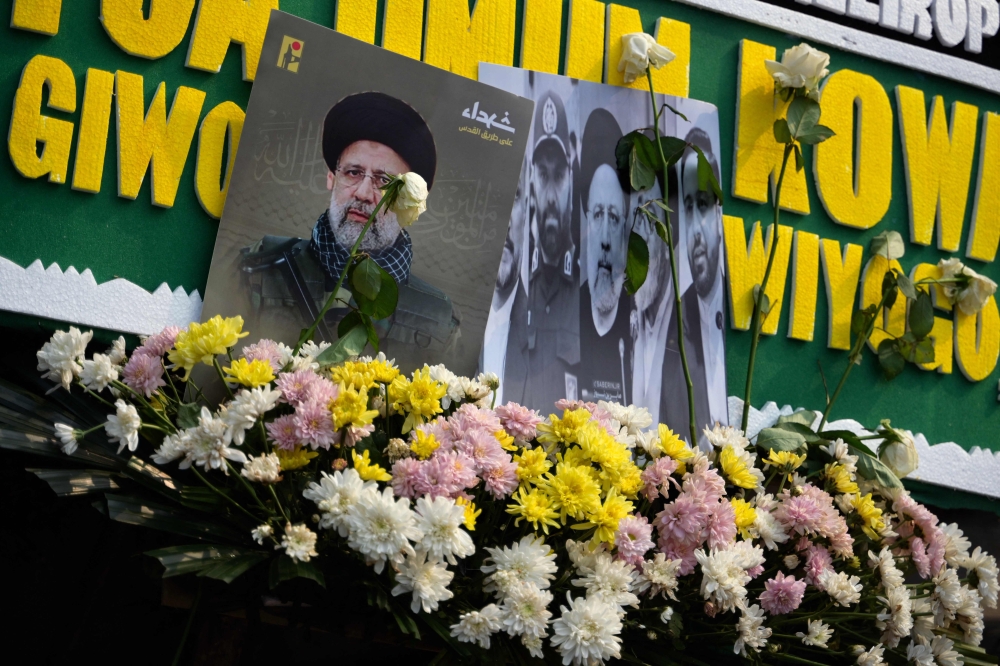 Portraits of Iran's late President Ebrahim Raisi are seen with flower bouquets outside the Iranian embassy in Jakarta May 21, 2024, following his death in a helicopter crash in a remote area of northwestern Iran. — AFP pic
