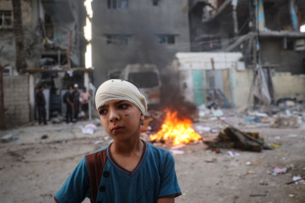 An injured Palestinian boy stands next to the rubble of a family house that was hit overnight in Israeli bombardment in the Tal al-Sultan neighbourhood of Rafah in southern Gaza on May 20, 2024, amid the ongoing conflict between Israel and the Palestinian Hamas group. — AFP pic