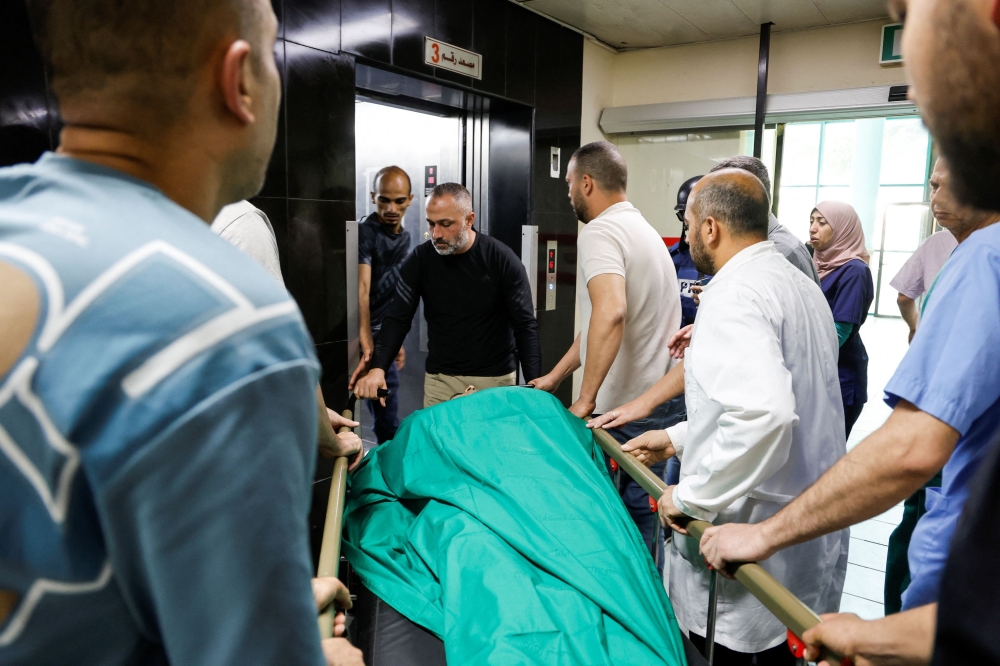 Palestinians carry the body of a person who was killed in an Israeli raid, at a hospital in Jenin camp, in the Israeli-occupied West Bank, May 21, 2024. — Reuters pic