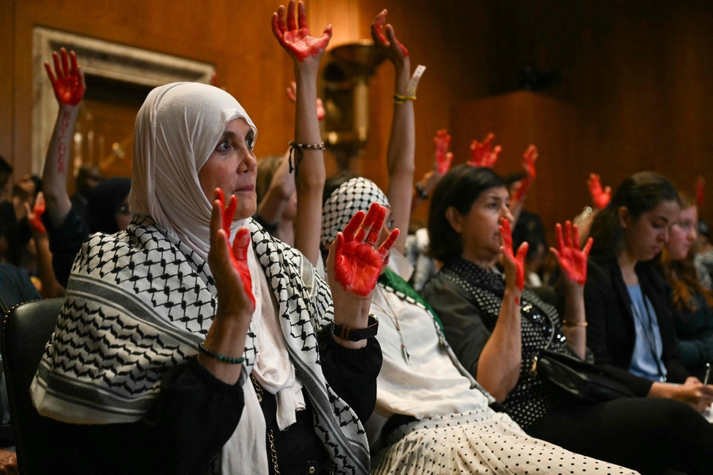 Pro-Palestinian demonstrators hold up painted hands in protest as US Secretary of State Antony Blinken testifies before the Senate Appropriations Subcommittee. — AFP pic