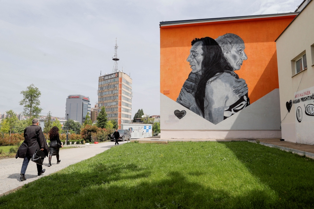 Pedestrians walk past a mural depicting Mustafa and Qerkica, a gay man with a disability and a transgender woman who have lived together and taken care of each other for many years in Pristina Kosovo, May 17, 2024. — Reuters pic