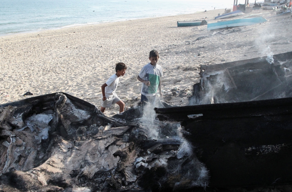 Palestinian children looks at a boat damaged in Israeli fire in Rafah. — Reuters pic