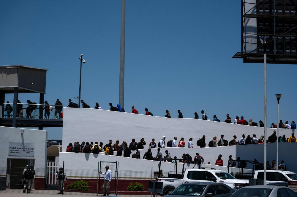 Asylum seekers walk for their asylum interview appointment with US authorities at the El Chaparral crossing port in Tijuana, Baja California State, Mexico, on May 18, 2024. — AFP pic