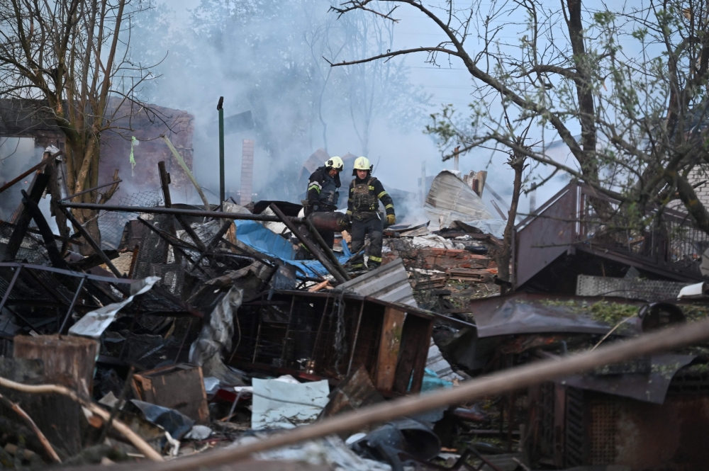 Firefighters clear debris from houses in the suburbs of Kharkiv destroyed by the attack of Russian drones. — AFP pic