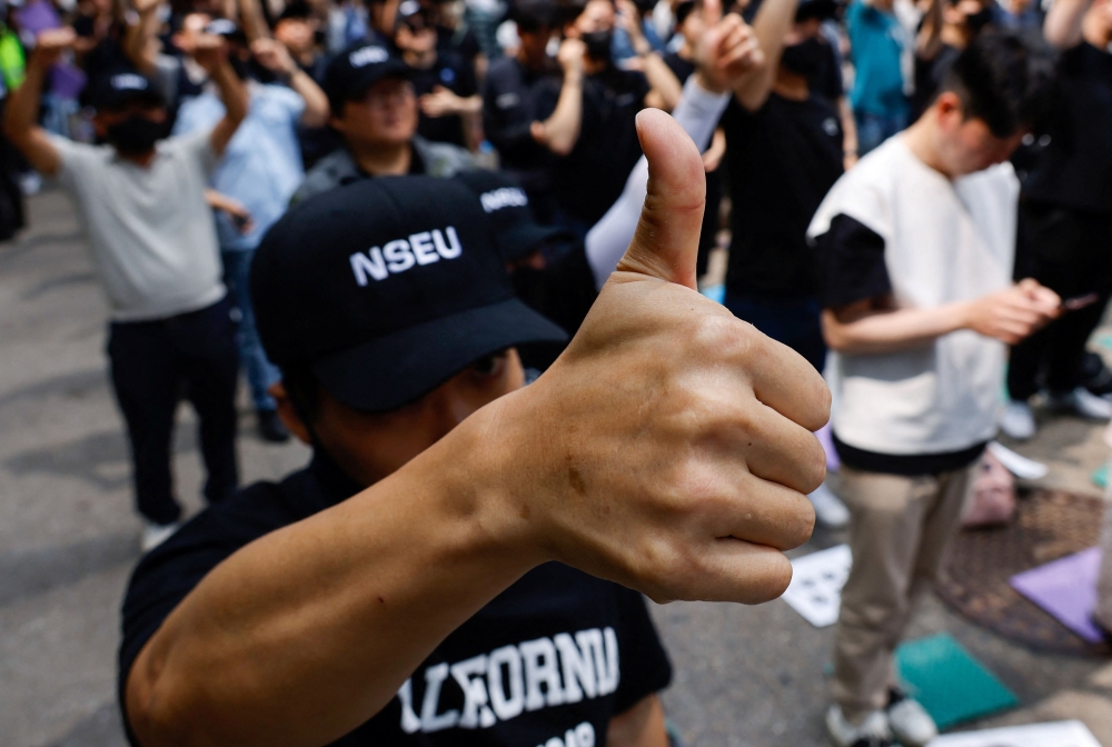 A member of the National Samsung Electronics Union (NSEU) shows a thumb-up gesture in front of the Samsung Electronics Seocho Building in Seoul May 24, 2024. — Reuters pic  