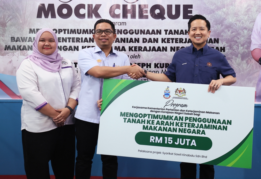 Agriculture and Food Security deputy minister Datuk Arthur Joseph Kurup (right) hands a RM15 million allocation mock cheque to Sawit Kinabalu Group representative Abd Halim Alimuddin at the Mini Library Internet Centre in Sungai Balung Estate, Tawau May 24, 2024. — Bernama pic
