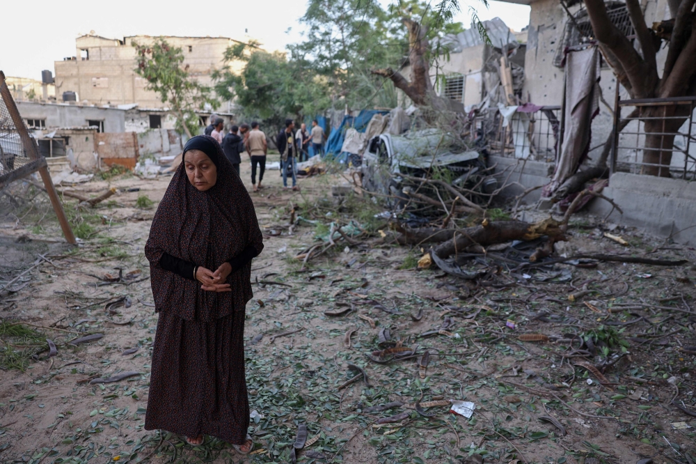 A Palestinian woman stands next to a damaged building after an Israeli airstrike in Rafah in the southern Gaza Strip May 22, 2024, amid the ongoing conflict between Israel and the Palestinian Hamas group. — AFP pic