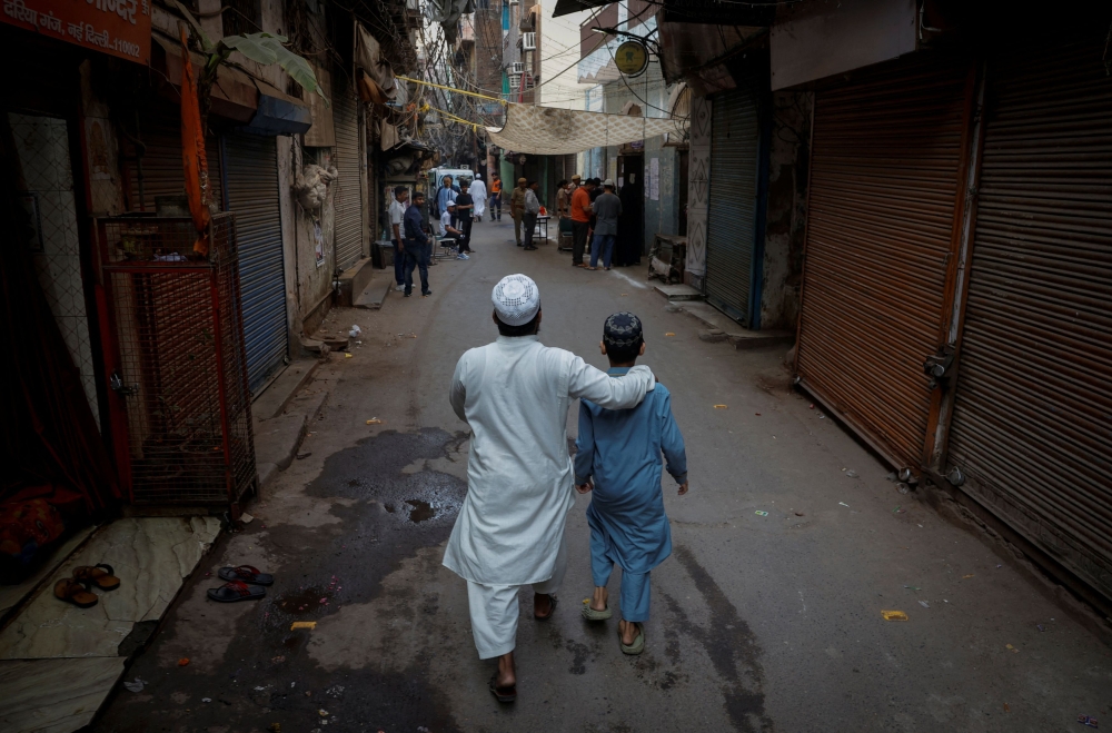 A man walks with his son towards a polling station to cast his vote during the sixth phase of the general election, in the old quarters of Delhi, India, May 25, 2024. — Reuters pic