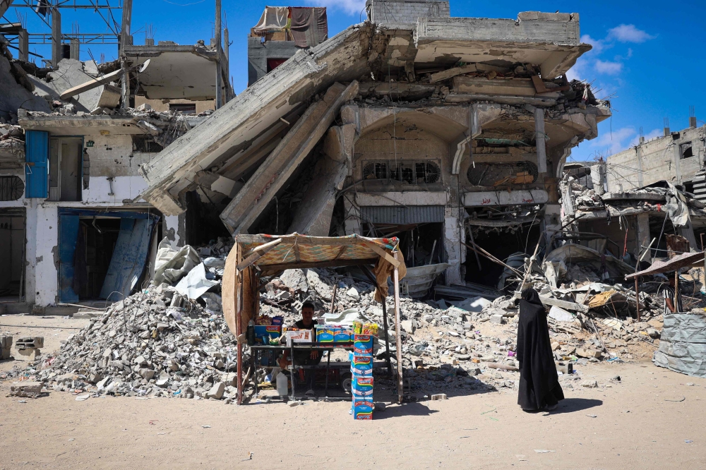 A displaced Palestinian man displays food items for sale in front of destroyed buildings in Khan Younis in the southern Gaza Strip on May 24, 2024, amid the ongoing conflict between Israel and the Hamas movement. — AFP pic