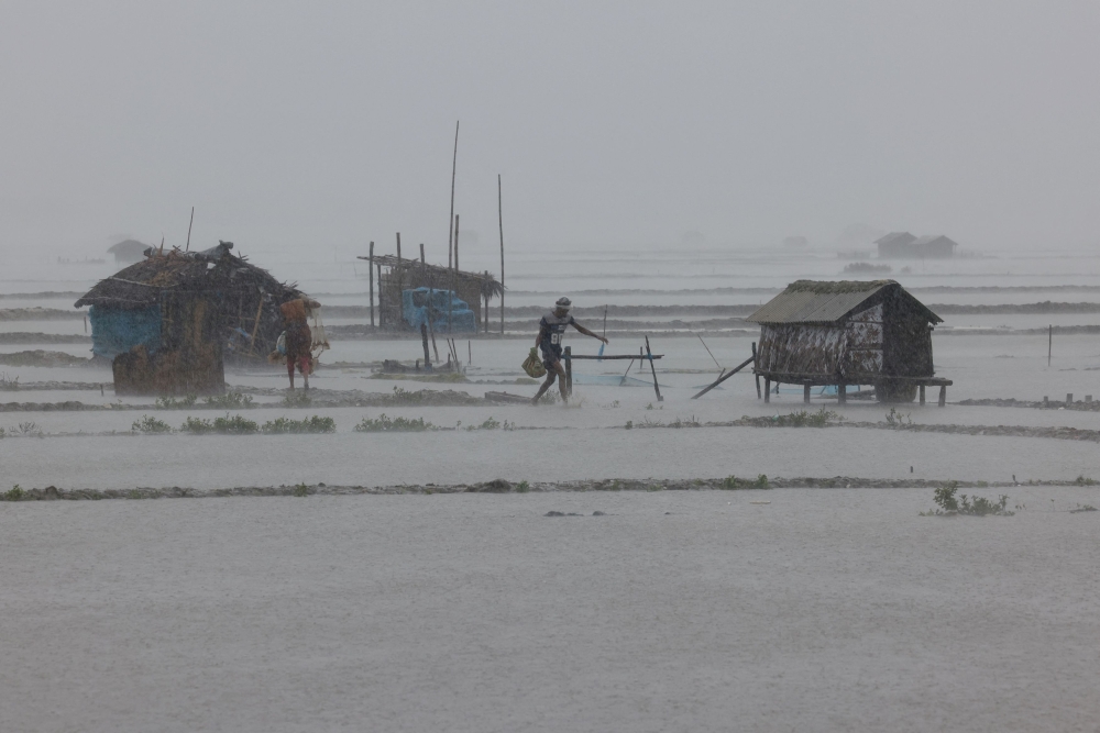 People walk along shrimp and crab farms that are flooded due to heavy rain as Cyclone Remal passes the country, in the Shyamnagar area of Satkhira, Bangladesh, May 27, 2024. — Reuters pic