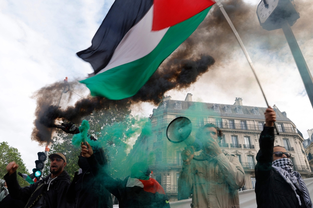 Protestors hold a Palestinian flag and flares during a demonstration called by French organisation ‘France Palestine Solidarite’ in Paris May 27, 2024. — AFP pic
