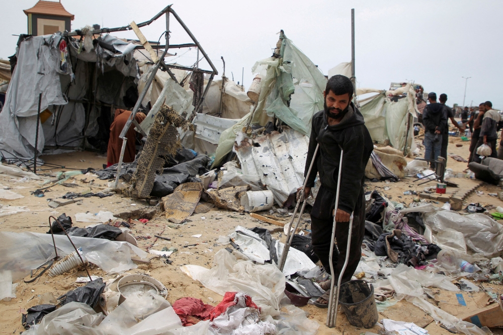 A man looks on as Palestinians inspect a tent camp damaged in an Israeli strike during an Israeli military operation, in Rafah, in the southern Gaza Strip, May 28, 2024. — Reuters pic