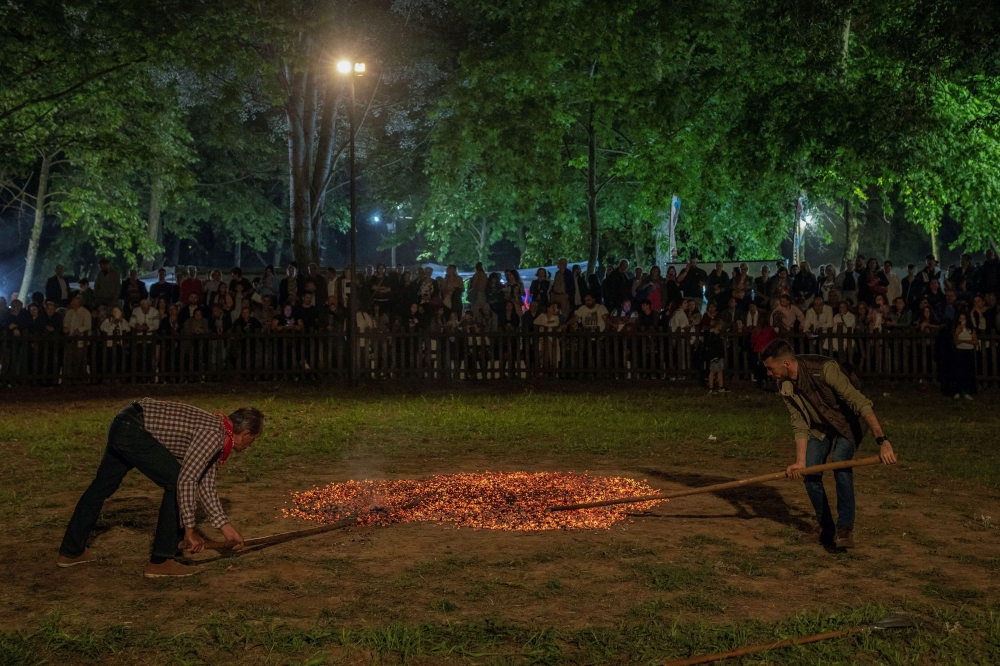 Men use wooden sticks to prepare the burning embers for the fire-walking ritual known as Anastenaria, on Saint Constantine and Saint Helen's Day marking the beginning of the fire-walking ritual known as Anastenaria, in Mavrolefki, Greece May 21, 2024. — Reuters pic  