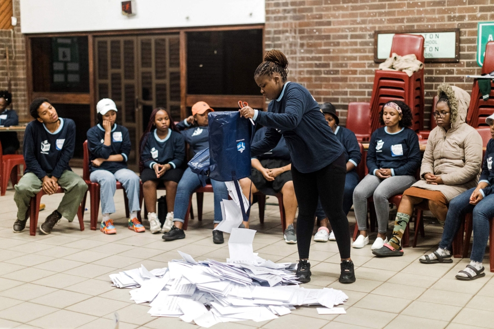 Electoral Commission of South Africa (IEC) official empty a ballot box during the vote counting process at the Addington Primary School voting station. — AFP pic