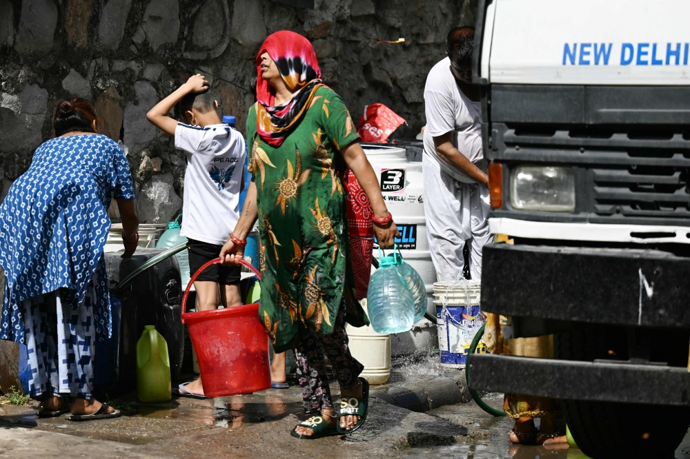 Residents fill containers with water supplied by a municipal tanker in New Delhi on May 30, 2024, amid ongoing heatwave. — AFP pic