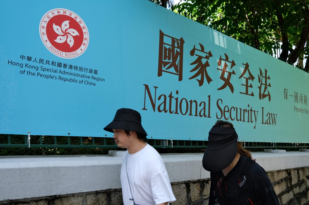 People walk past a banner for the National Security Law in Hong Kong July 15, 2020. — AFP pic
