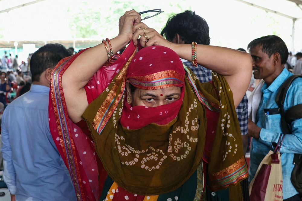 A polling official ties a cloth around her face at a distribution center in Varanasi on May 31, 2024, on the eve of the seventh and final phase of voting in India's general election. — AFP pic