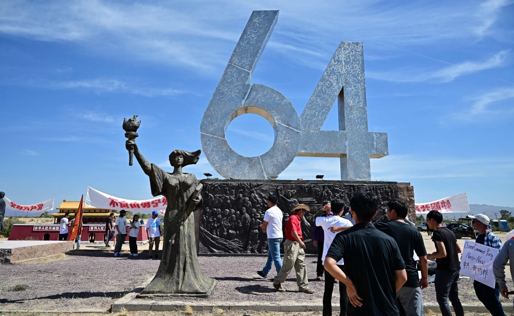 People gather around artist Chen Weiming’s ‘6-4’ and ‘Goddess of Democracy’ sculptures as they commemorate the 35th anniversary of the June 4, 1989 Tiananmen massacre at Liberty Sculpture Park in the Mojave Desert town of Yermo, California. — AFP