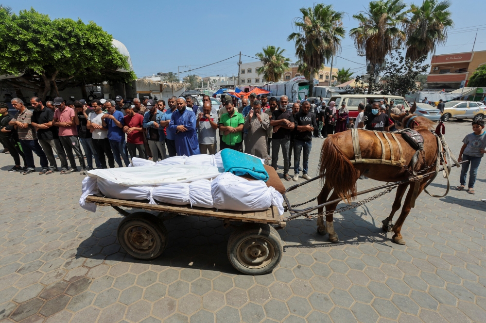 Mourners pray next to bodies of Palestinians killed in Israeli strikes as they are loaded on a horse-drawn cart before being transported to a cemetery, at Al-Aqsa hospital in Deir Al-Balah in the central Gaza Strip, June 3, 2024. — Reuters pic 