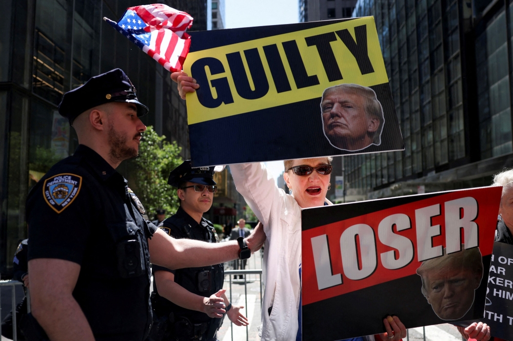 An anti-Trump protester holds placards outside Trump Tower, the day after a guilty verdict in Republican presidential candidate and former US President Donald Trump's criminal trial over charges that he falsified business records to conceal money paid to silence porn star Stormy Daniels in 2016, in New York City May 31, 2024. — Reuters pic