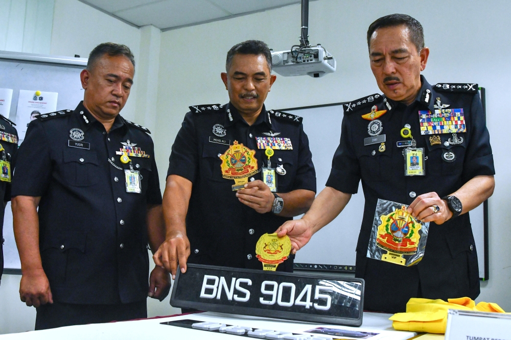 Kelantan police chief Datuk Muhamad Zaki Harun with the fake emblems. He said all suspects, aged between their 20s and 30s, were detained on May 24 and 25 in Bachok and around Setia Alam, Selangor. — Bernama pic 