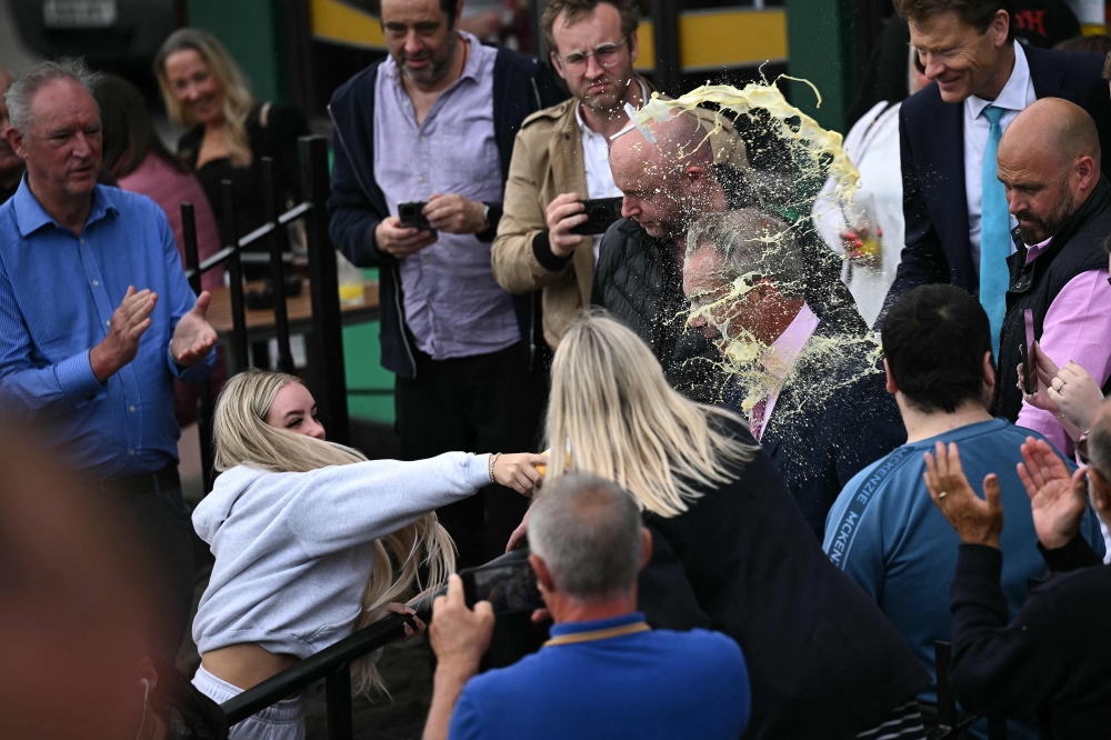 A person throws a drink in the face of newly appointed leader of Britain's right-wing populist party, Reform UK, and the party's parliamentary candidate for Clacton, Nigel Farage, during his general election campaign launch in Clacton-on-Sea, eastern England, on June 4, 2024. Nigel Farage on Monday said he would stand as a candidate for the anti-immigration Reform UK party in Britain's general election next month, after initially ruling out running. 