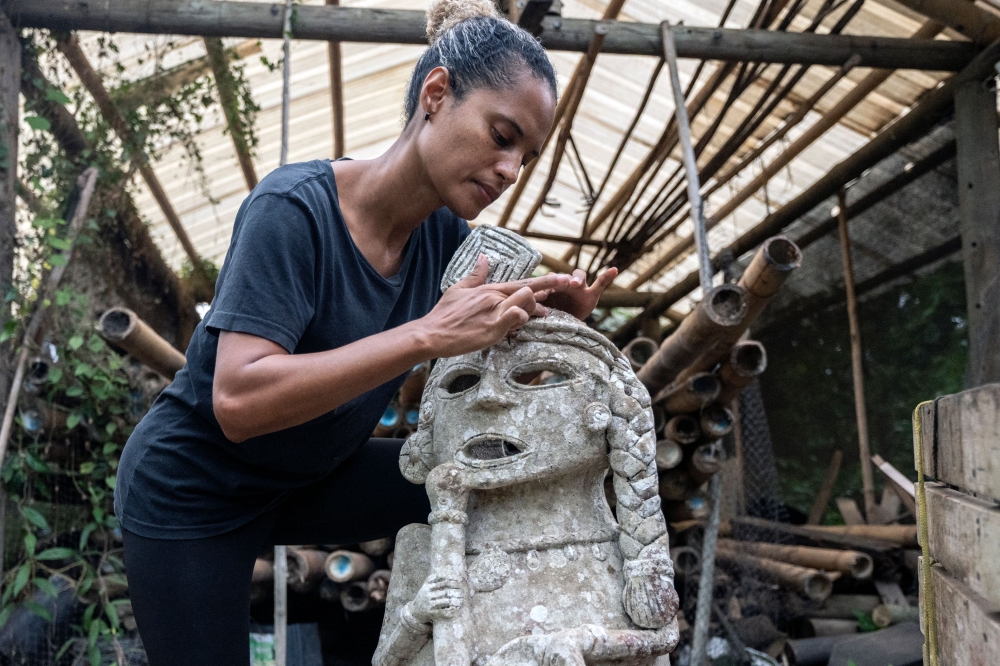 Tatiana Orrego restores a clay sculpture before it heads to its new underwater home. — AFP pic
