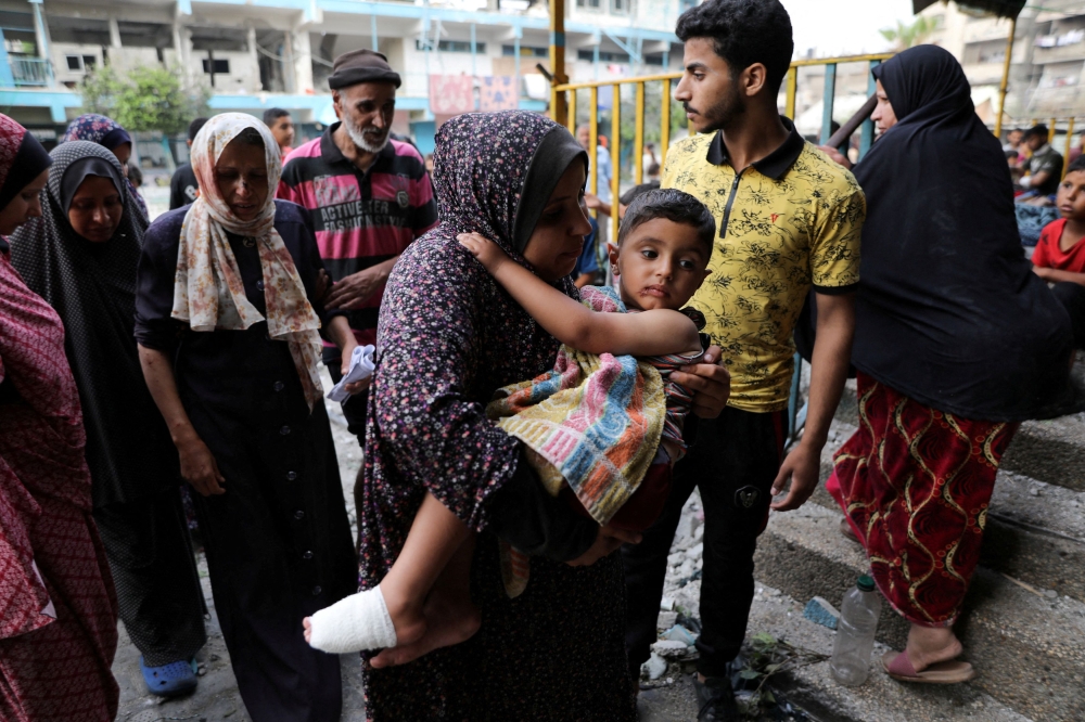 File phto of a woman carrying a child at the site of an Israeli strike on a UNRWA school sheltering displaced people, amid the Israel-Hamas conflict, in Nuseirat refugee camp in the central Gaza Strip, June 6, 2024. ― Reuters pic