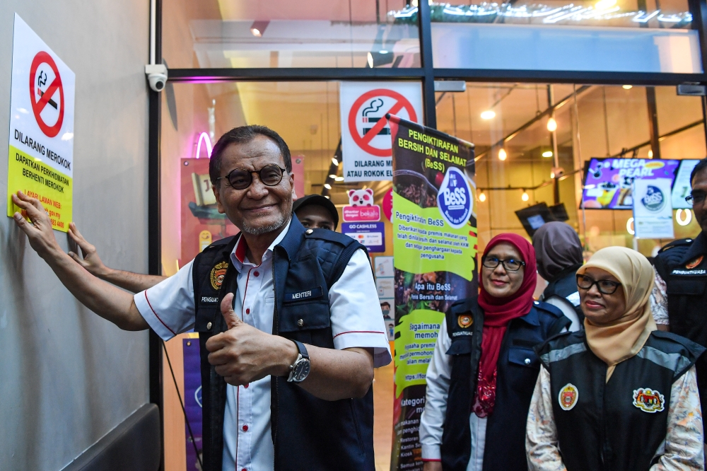 Health Minister Datuk Seri Dzulkefly Ahmad (left) stocks an anti-smoking sign during the Clean, Smoke-Free Premises (BeBAs) walkabout programme at Port Dickson Waterfront June 8, 2024. — Bernama pic