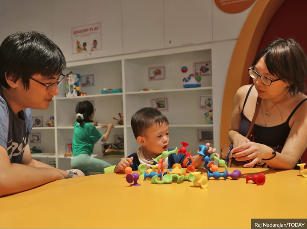 Summer Chen (right) with her husband and son at the Toy Library, a dedicated section for children aged six and under at Punggol Regional Library in Singapore May 27, 2024. — TODAY pic