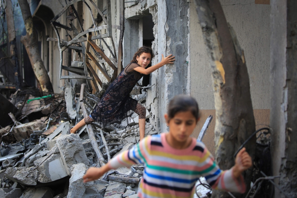 A Palestinian girl climbs over debris after Israeli forces attacked the Nuseirat camp. — AFP pic