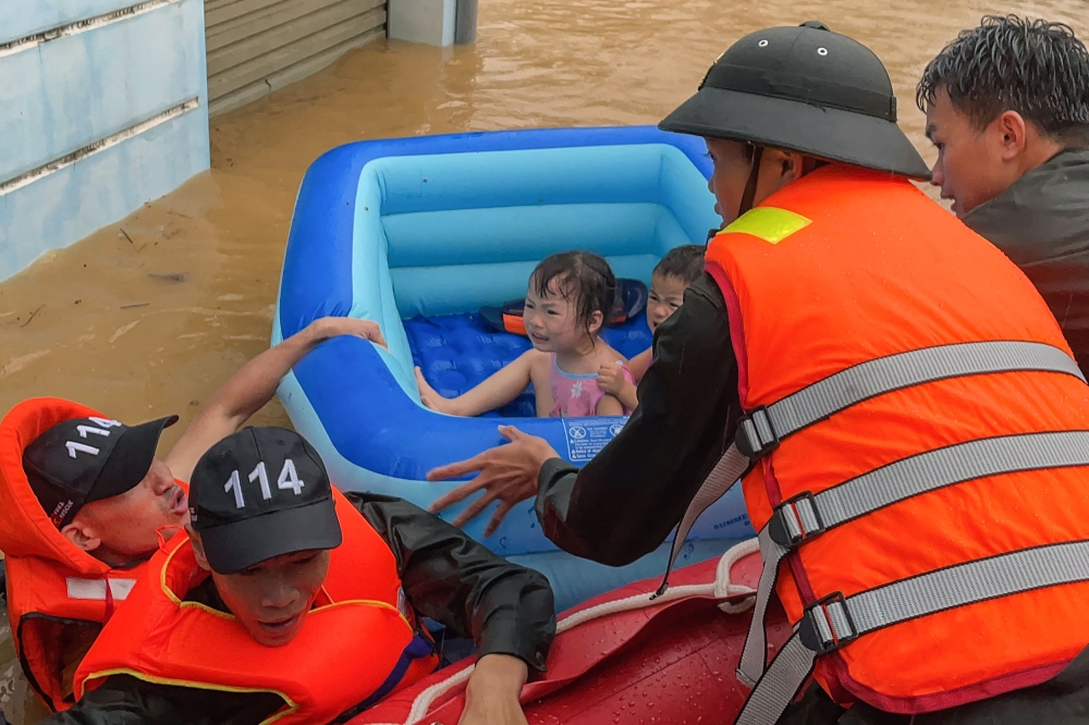 Rescuers help children in an inflatable dinghy to get out of flood waters after heavy rain in Vietnam's northern Ha Giang province June 10, 2024. — AFP pic