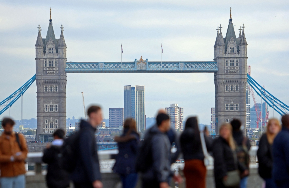 People walk over London Bridge looking at a view of Tower Bridge in the City of London financial district in London October 25, 2023. — Reuters pic  