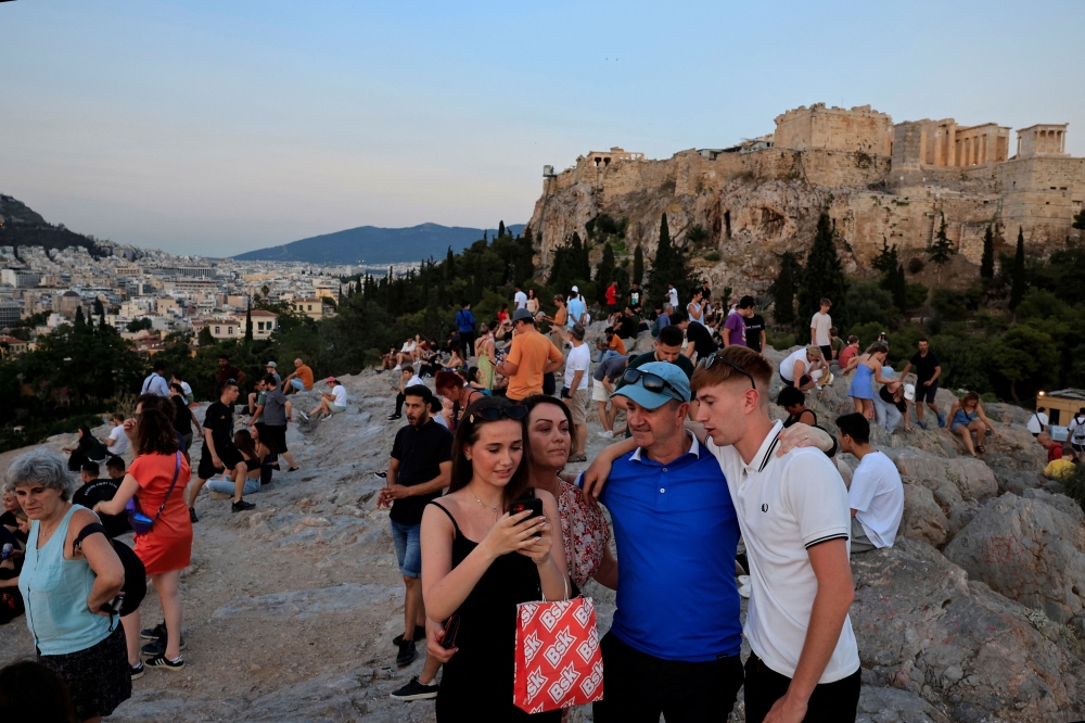 Tourist and locals enjoy a sunset at Areopagus Hill overlooking the Acropolis archaeological site, amid high temperatures in Athens, Greece, June 9, 2024. — Reuters pic