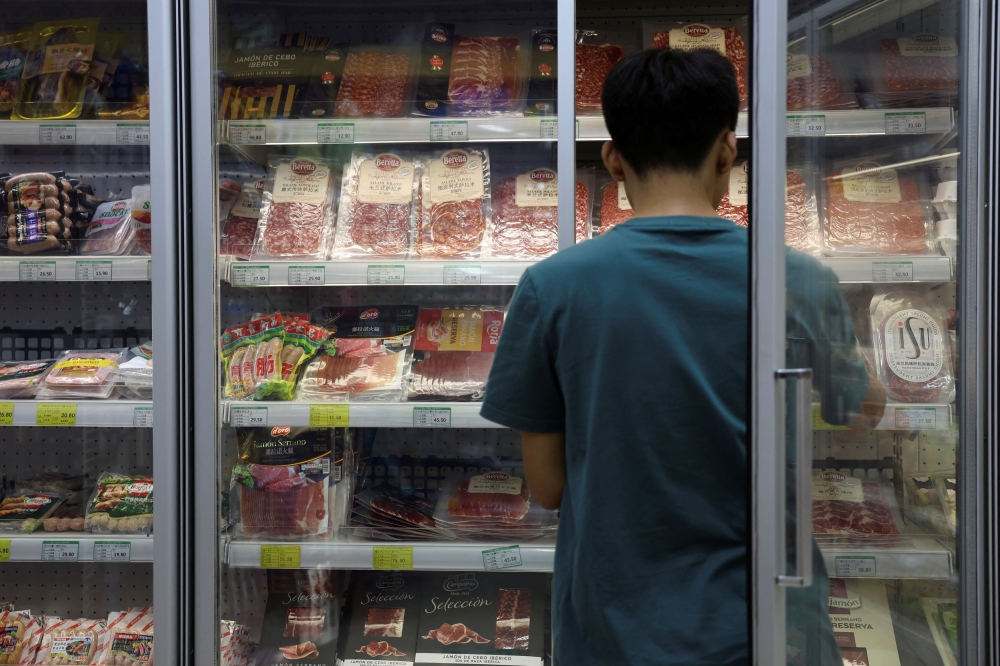 A staff member stocks a freezer where pork and other meat products are displayed, at a supermarket in Beijing June 13, 2024. — Reuters pic  