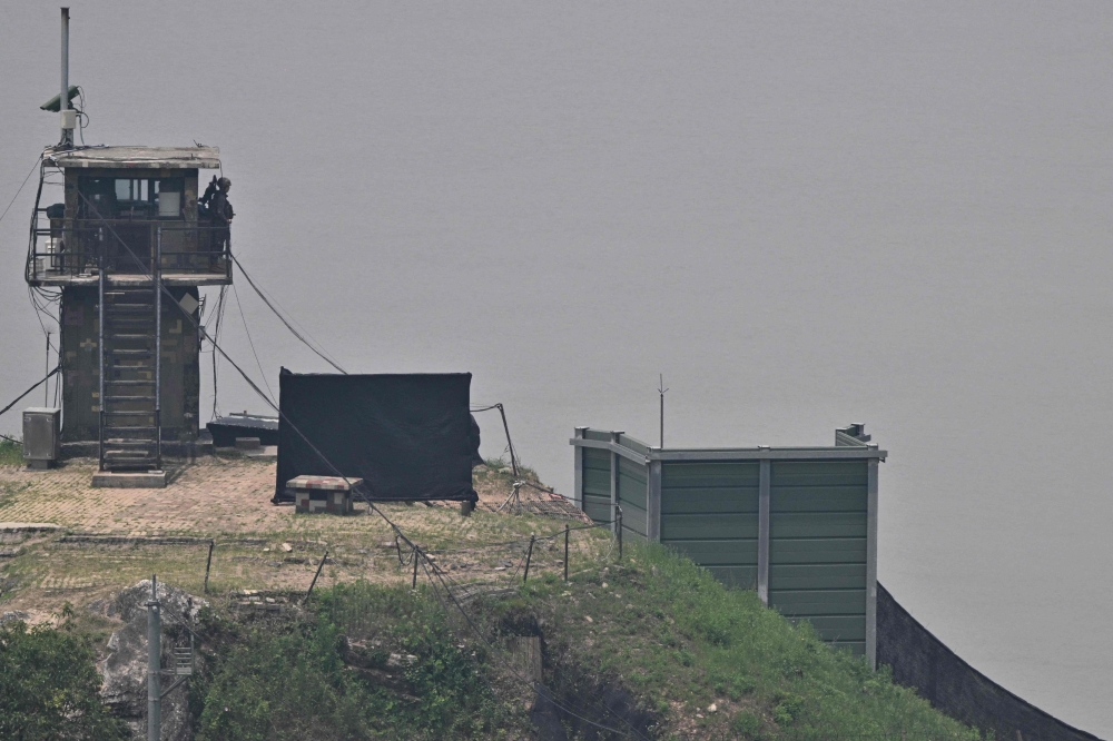 File photo of a South Korean soldier standing guard near a military facility (right, green box) where loudspeakers dismantled in 2018 used to be, near the demilitarised zone separating the two Koreas in Paju on June 11, 2024. — AFP pic