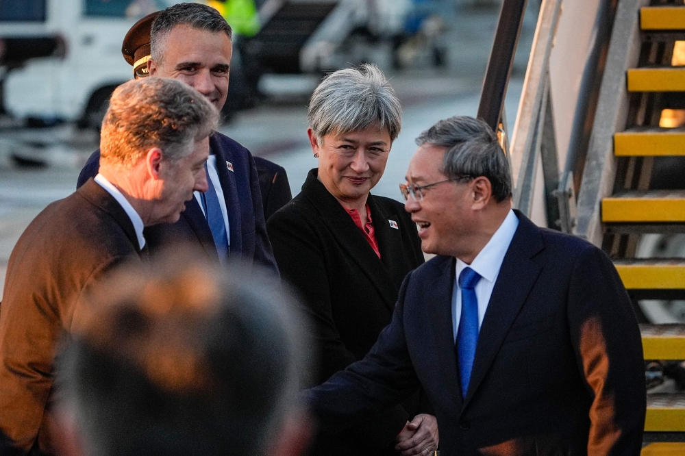 China’s Premier Li Qiang (right) greets Australia’s Foreign Minister Penny Wong (centre), South Australia’s Premier Peter Malinauskas (second left) and other officials at Adelaide Airport in Adelaide on June 15, 2024. — AFP pic